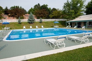 Relax by the pool surrounded by lush greenery and a seating area.