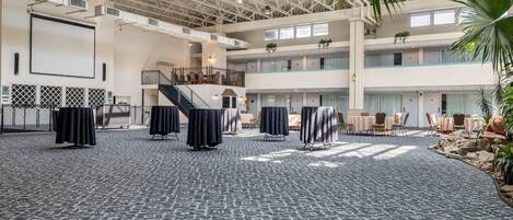 A spacious indoor area with a high ceiling, multiple levels, and a central staircase.