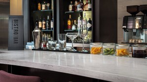 Una zona de bar con mostrador de mármol, vasos y botellas.
