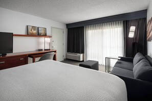 A hotel room with a large bed, a desk with a computer, a TV, a sofa, and a window with curtains. - Courtyard Fremont Silicon Valley (Fremont)