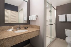 A modern bathroom with a granite countertop sink, a glass shower enclosure, and a toilet. - Courtyard Fremont Silicon Valley (Fremont)