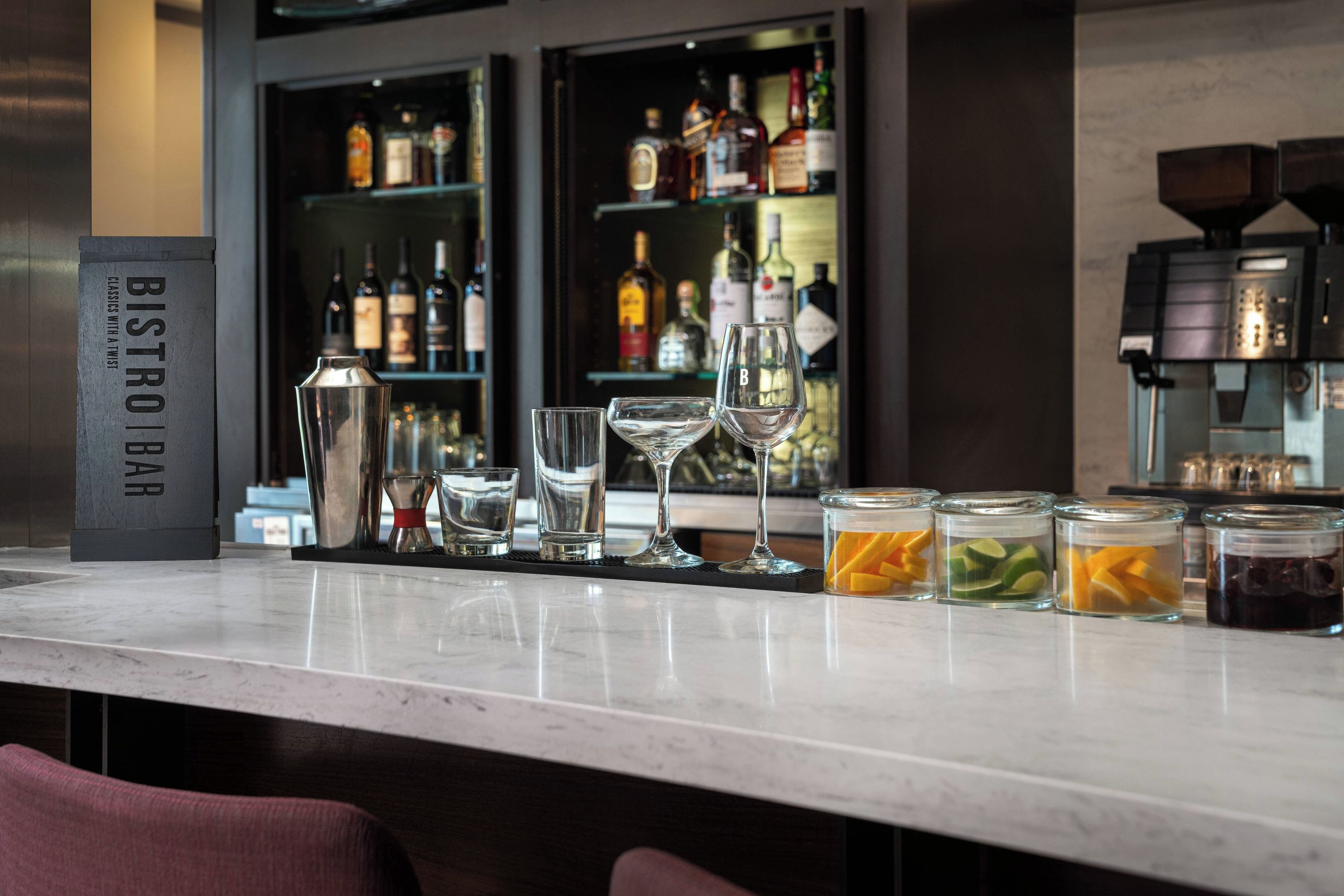 A bar area with a bar counter, various glasses, bottles, and a coffee machine.