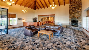 A spacious living room with leather sofas, a coffee table, and a stone fireplace. - Red Lion Hotel & Conference Center Ellensburg (Ellensburg)