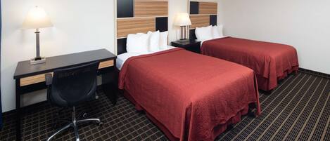 Habitación de hotel con dos camas, un escritorio, una silla y dos mesitas de noche con lámparas.