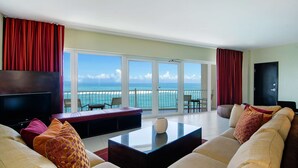 Amplia sala de estar con un sofá grande, una mesa de centro y un televisor de pantalla plana. La habitación cuenta con ventanas amplias y vistas al océano.