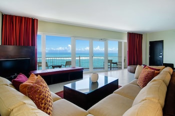 Relax in this spacious living room with a large flat-screen TV, comfortable sofa, and balcony offering unobstructed ocean views. at The Condado Plaza Hotel