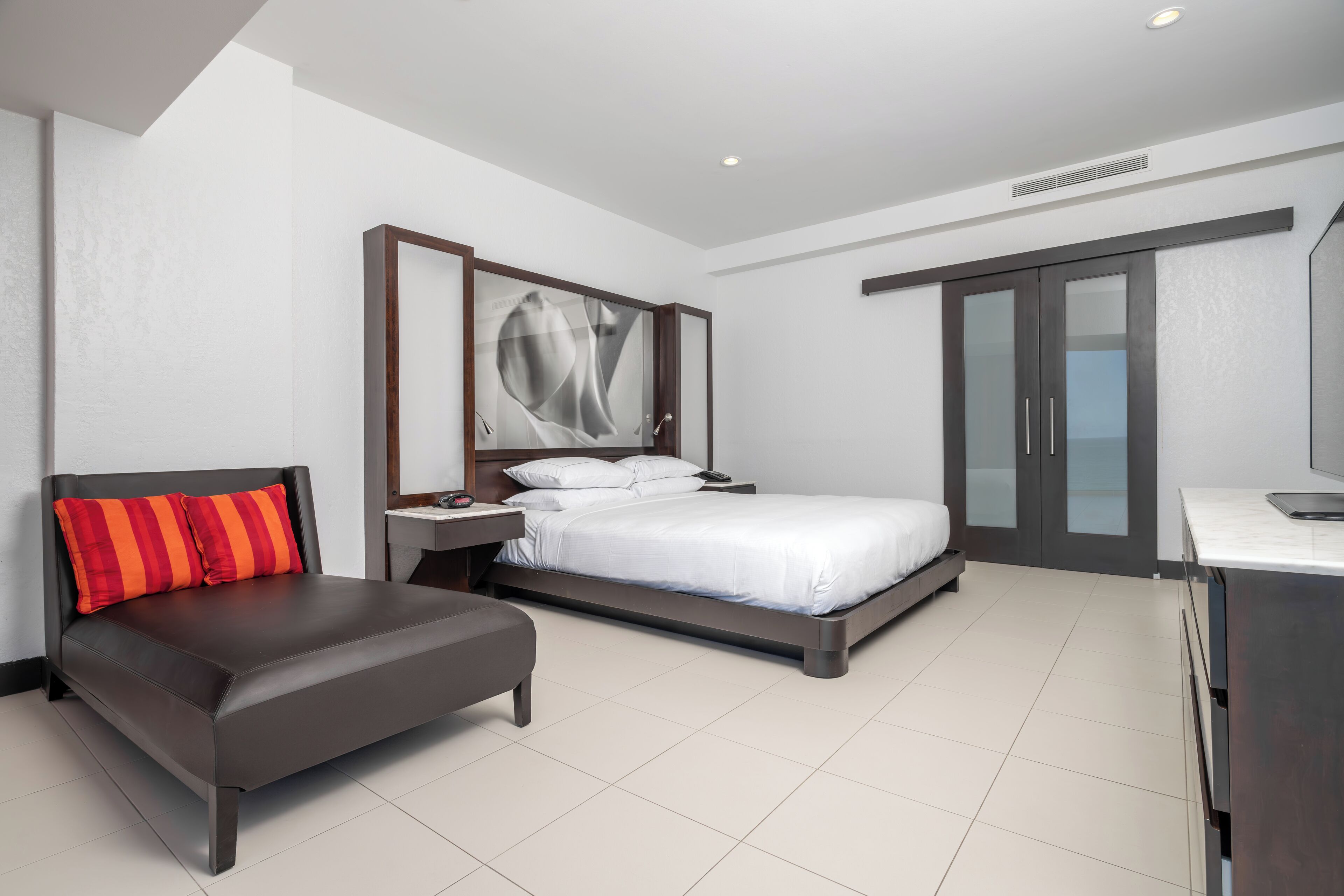 Ein modernes Hotelzimmer mit Bett, einer Sitzecke, einem Schreibtisch und einem Kleiderschrank.