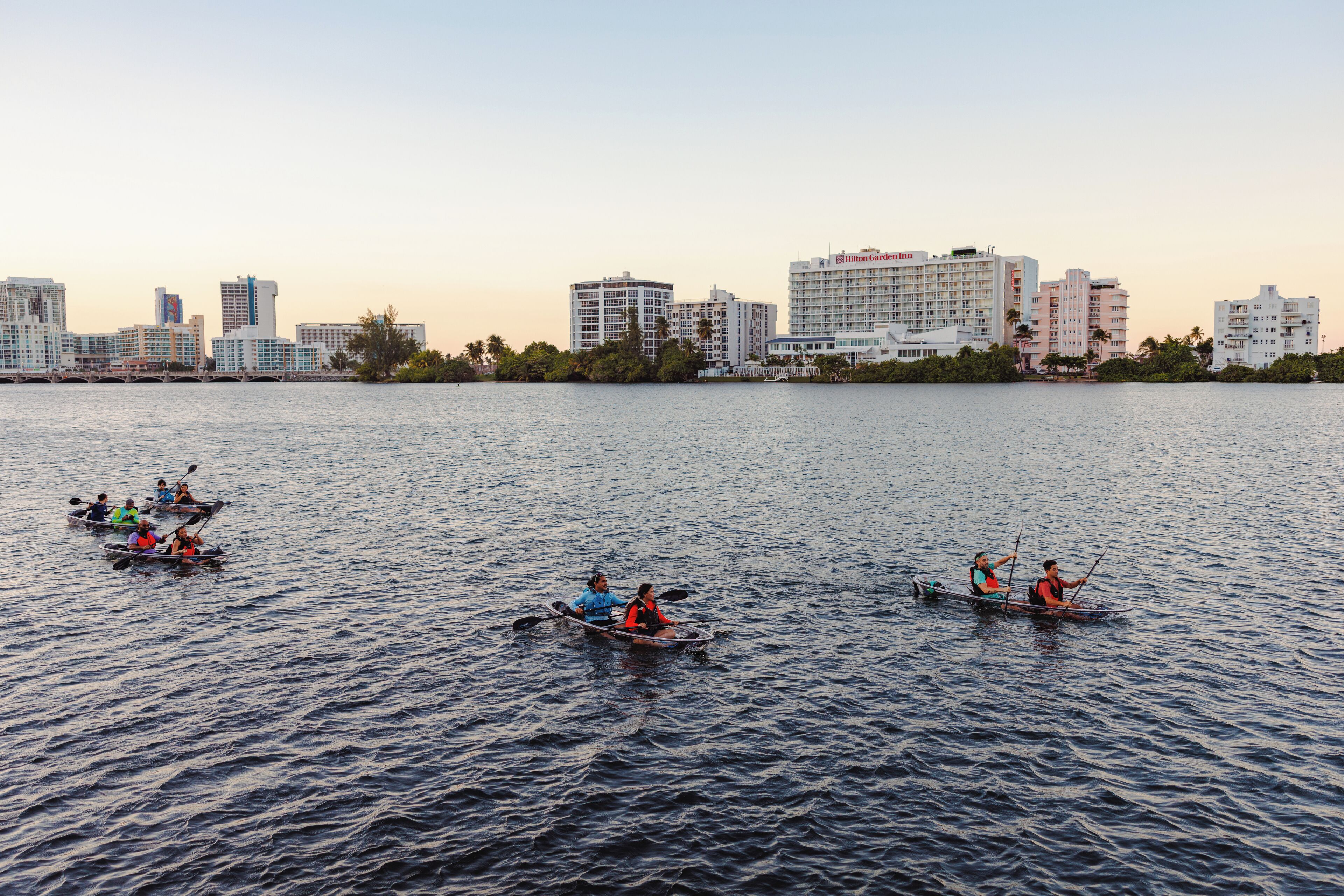 A waterfront cityscape with several kayaks on the water.