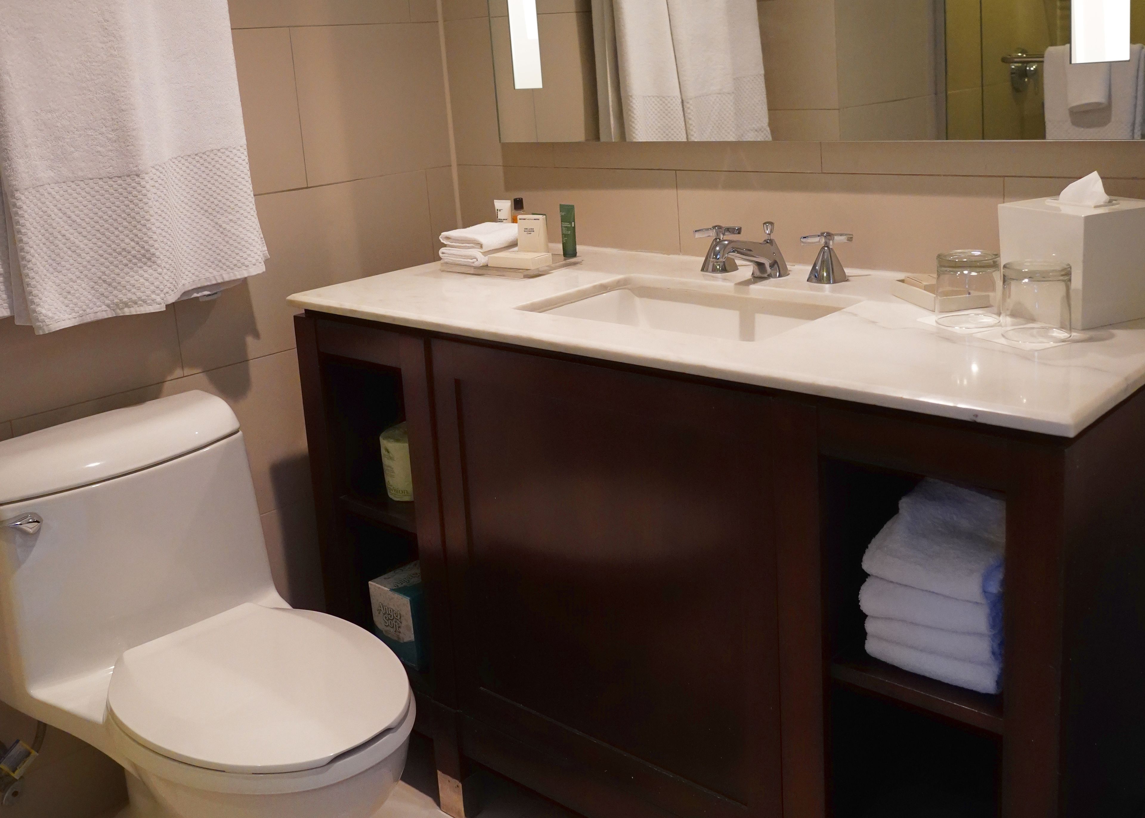 A bathroom with a toilet, a sink with a mirror above it, and a cabinet below.