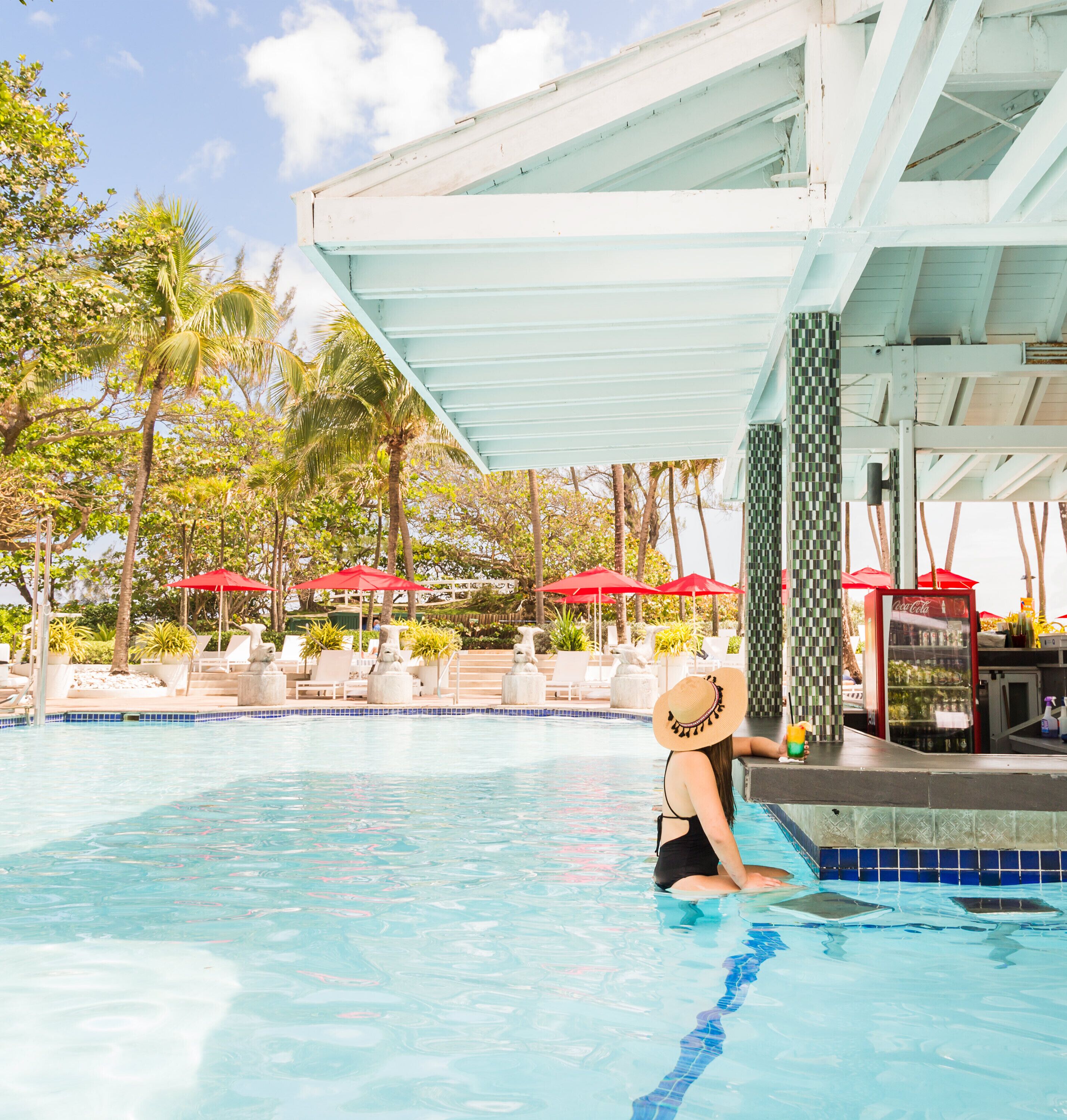 A pool area with lounge chairs, a Coca-Cola vending machine, and a covered seating area.