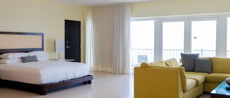 Una habitación de hotel con cama, sofá, escritorio y ventana con cortinas.