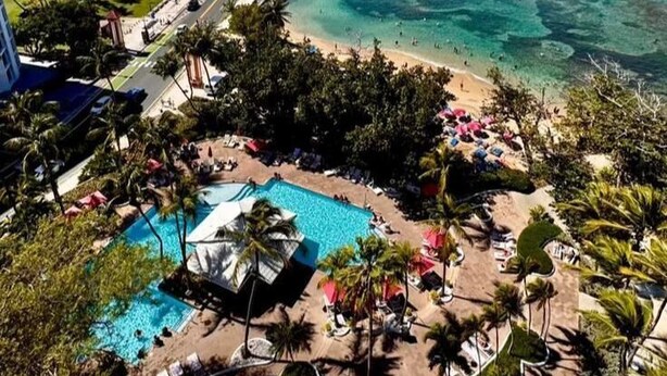 Un resort con piscina, playa y un puente.