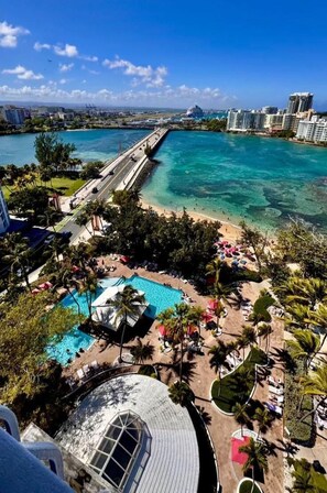 Un complex turístic amb piscina, platja i un pont.