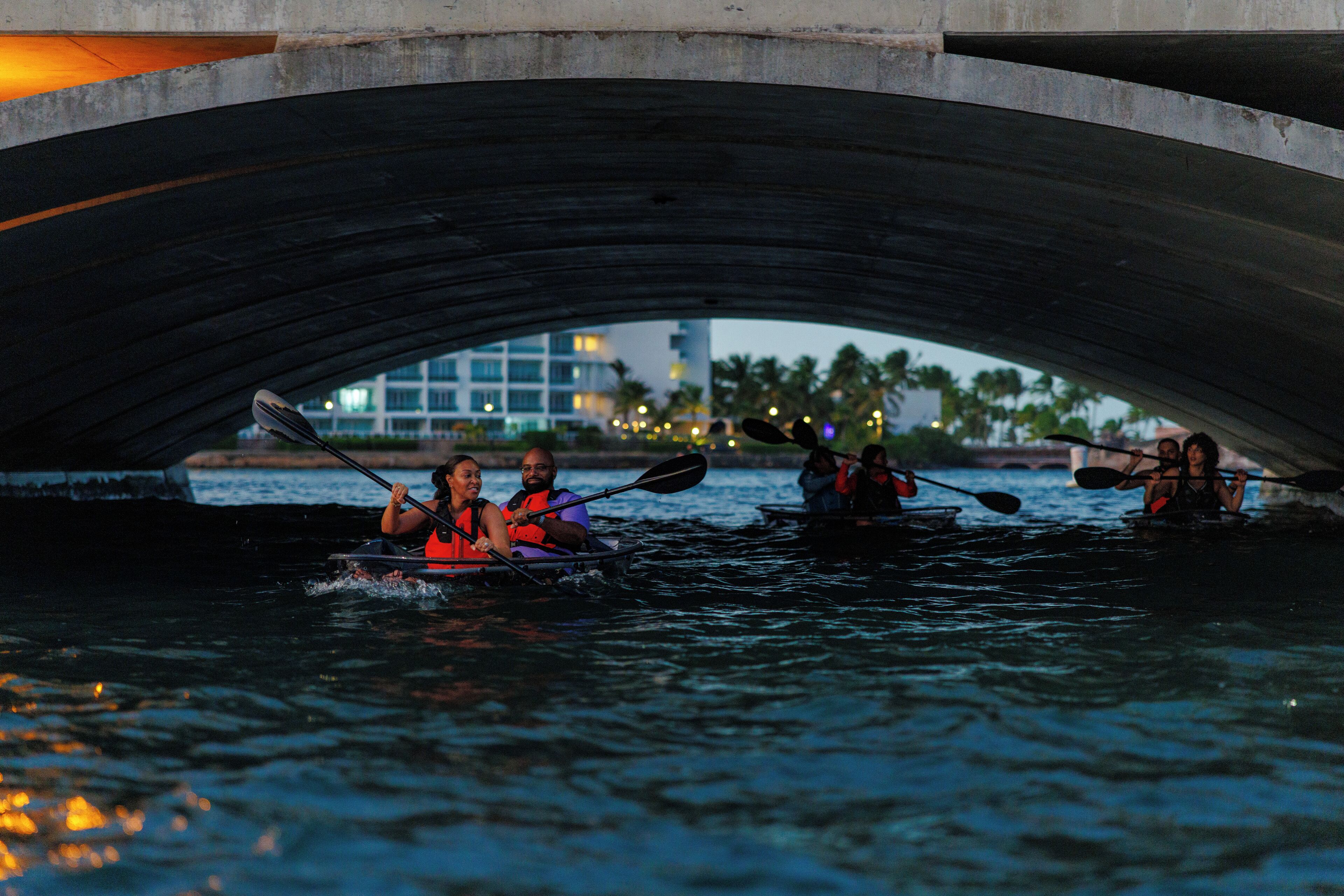 A group of people kayaking under a bridge.