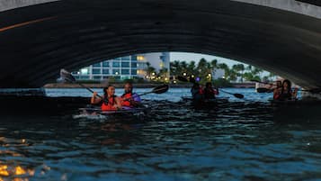 A group of people kayaking under a bridge.
