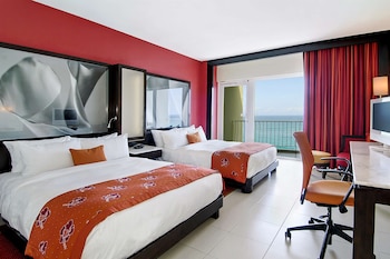 Two beds with white linens and floral bedspreads, a flat-screen TV, and a desk with a chair. at The Condado Plaza Hotel