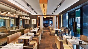A modern restaurant with long tables, comfortable seating, and a view of the street. - Le Metropolitan Paris Tour Eiffel, a Tribute Portfolio Hotel (Paris)