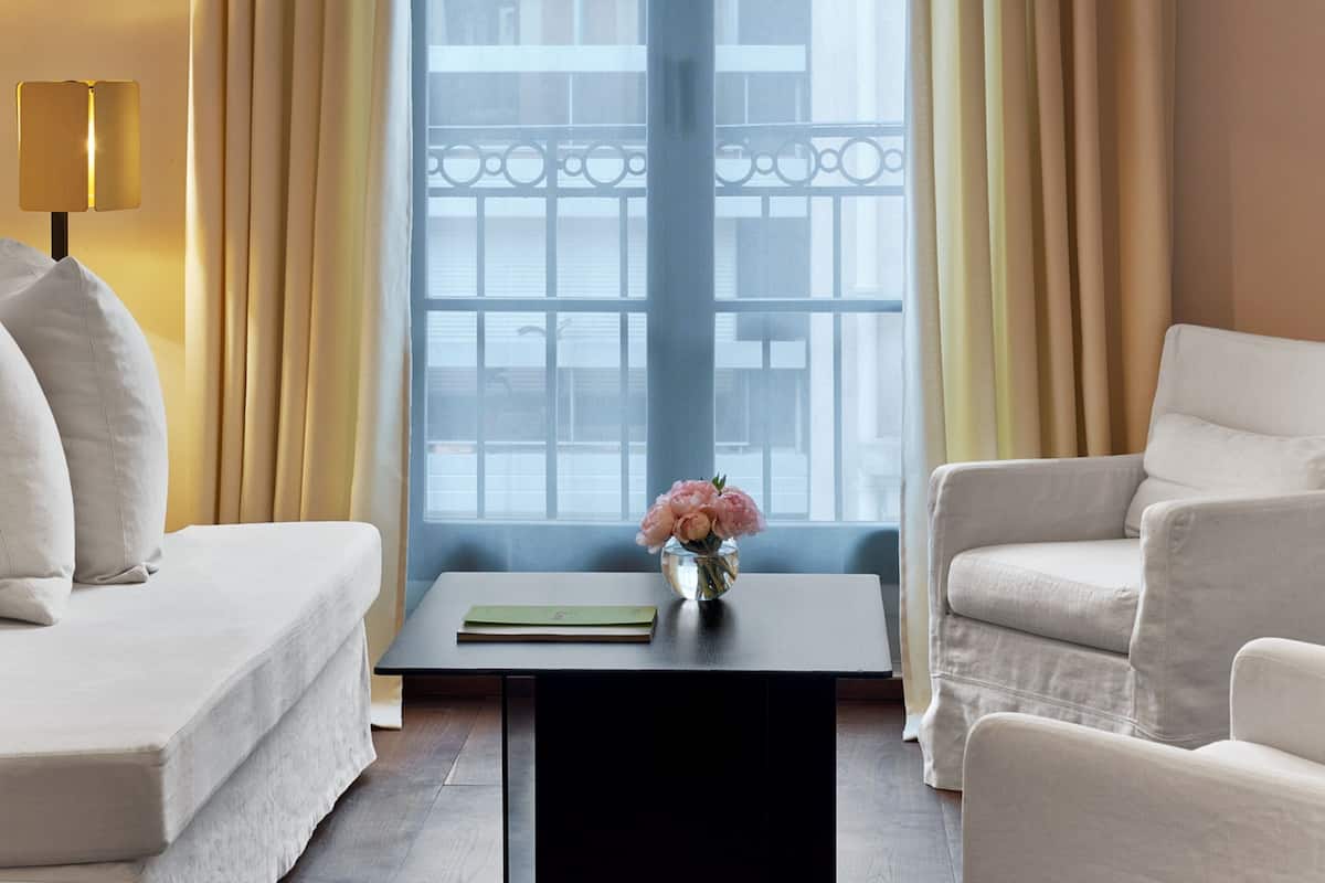 A modern living room with a sofa, armchairs, a coffee table, and a vase of flowers.