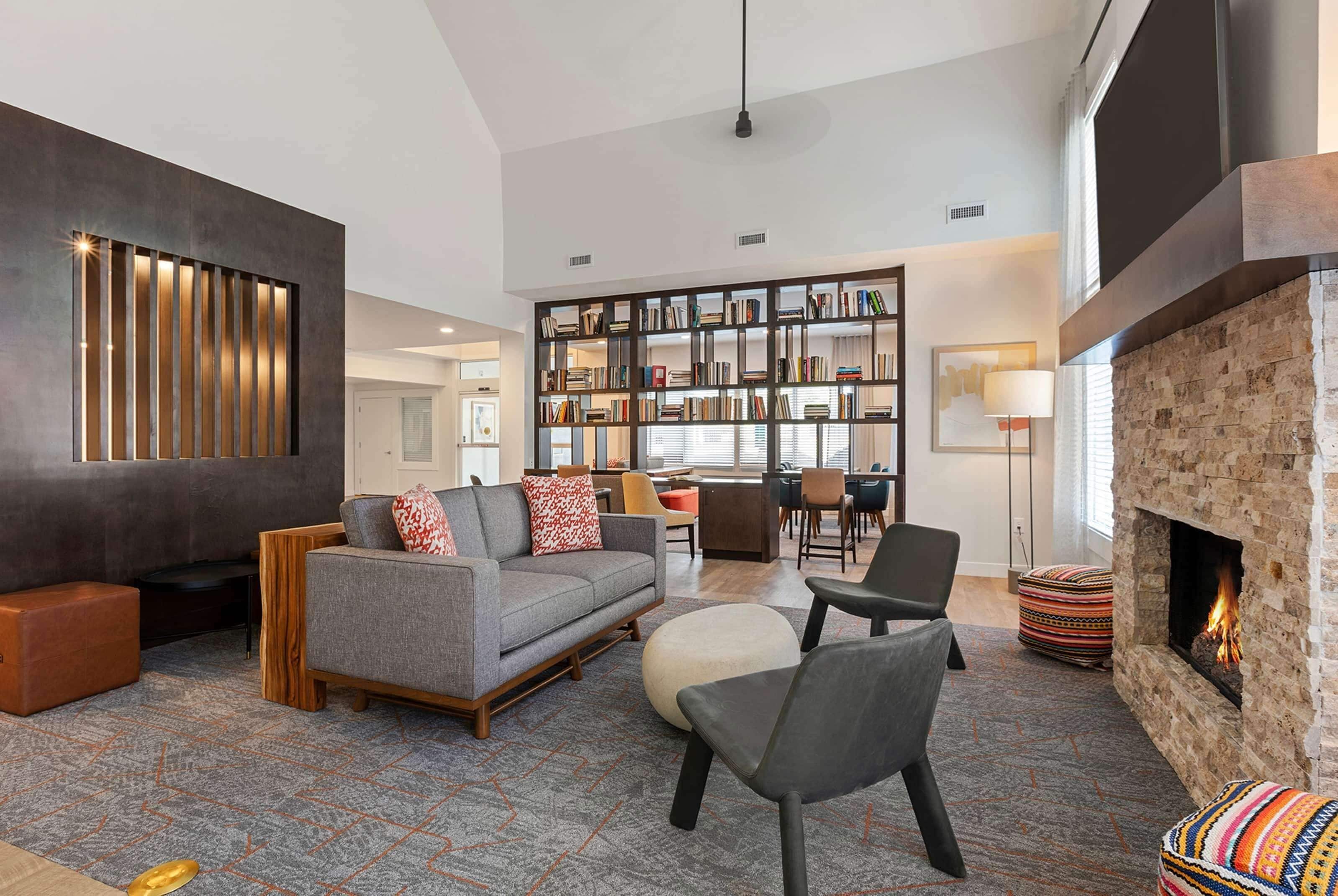 A spacious living room with a fireplace, a large bookshelf, and a modern sofa.