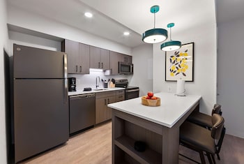 A spacious living area with a sofa, chairs, a bookshelf, and a dining area with a table and chairs. at WaterWalk Extended Stay by Wyndham Atlanta Perimeter