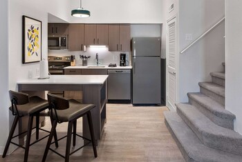 A modern kitchen with a refrigerator, microwave, and sink, and a dining area with a table and chairs. at WaterWalk Extended Stay by Wyndham Atlanta Perimeter