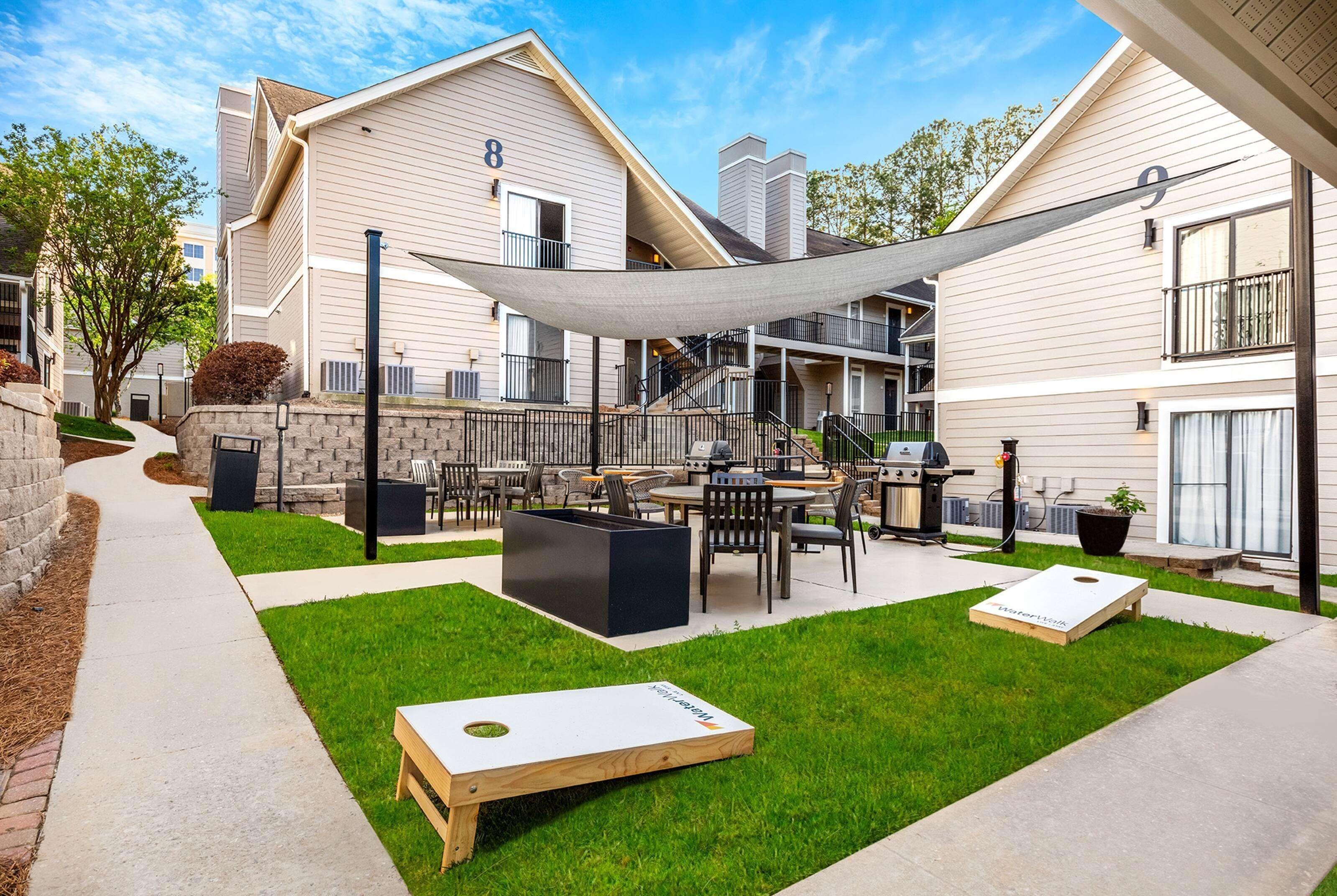 A courtyard with outdoor seating, a barbecue area, and a large shade sail.