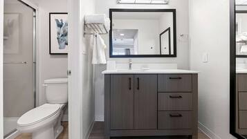 A modern bathroom with a toilet, a vanity with a mirror, and a towel rack.