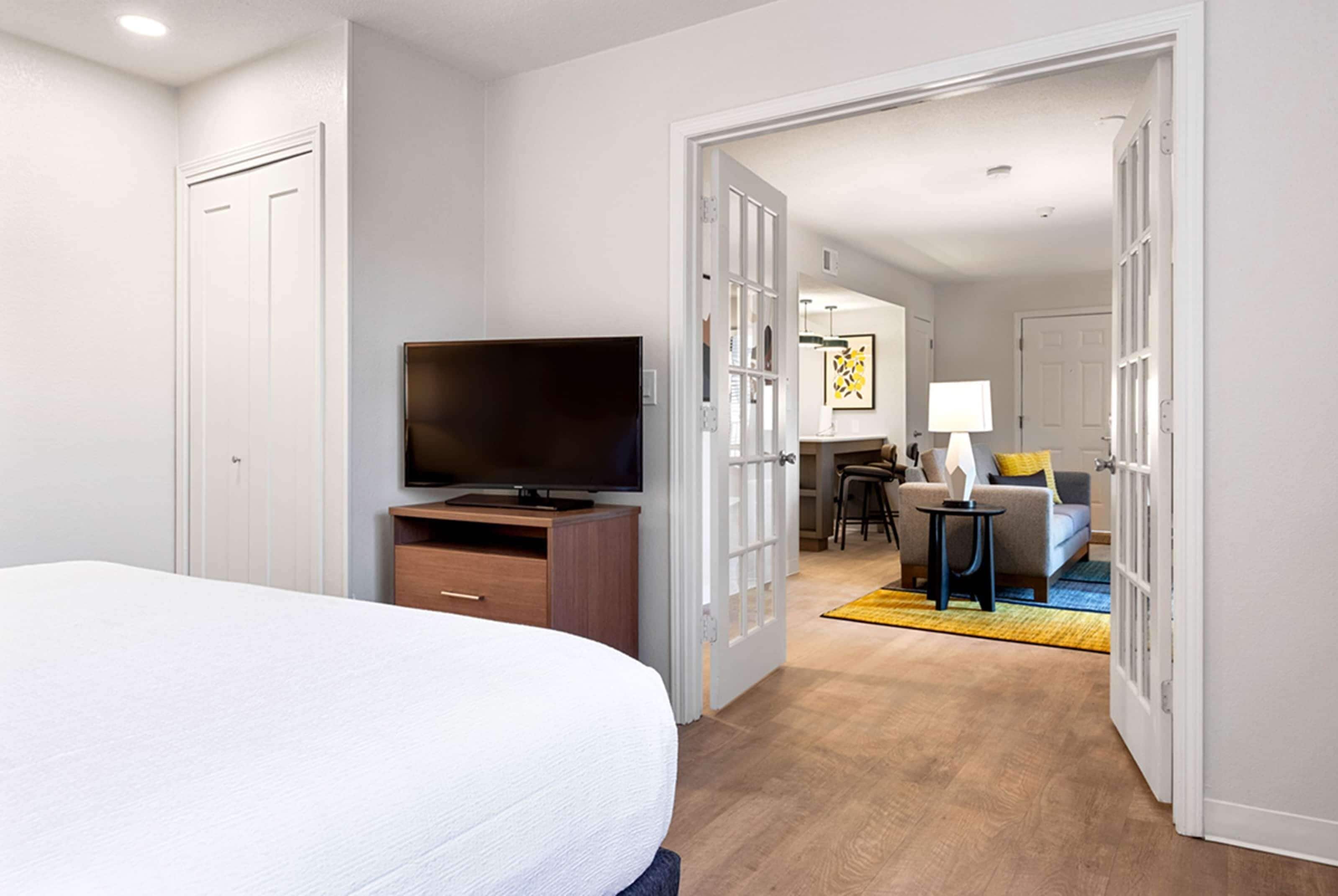 Une chambre d’hôtel équipée d’un lit, d’une télévision, d’un bureau et offrant une vue sur l’espace de vie.