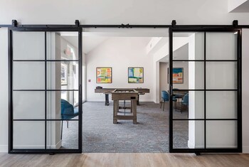 A modern kitchen with a central island, bar stools, a microwave, a refrigerator, and a staircase. at WaterWalk Extended Stay by Wyndham Atlanta Perimeter