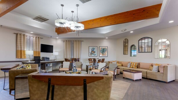 Amplia sala de estar con mesa de comedor de madera, sofás y  área de cocina con televisor de pantalla plana.