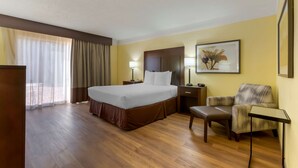 A hotel room with a large bed, a desk, a chair, and a nightstand.