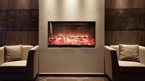 A modern interior with a fireplace, two sofas, and dark wooden paneling. - Hotel Domicil Hamburg by Golden Tulip (Hamburg)