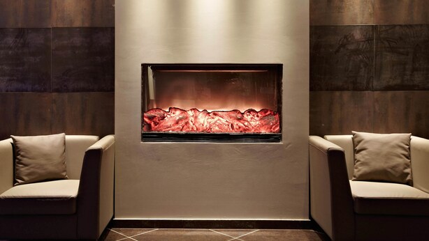 Ein modernes Interieur mit Kamin, zwei Sofas und dunklen Holzpaneelen.