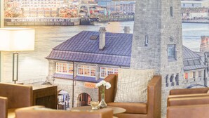 A cozy room with a view of a harbor, featuring a stone wall clock, a fireplace, and a table with a vase. - Hotel Domicil Hamburg by Golden Tulip (Hamburg)