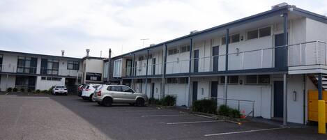 A multi-story motel with a parking lot, several cars parked, and a sign for 'Empire Grill'.