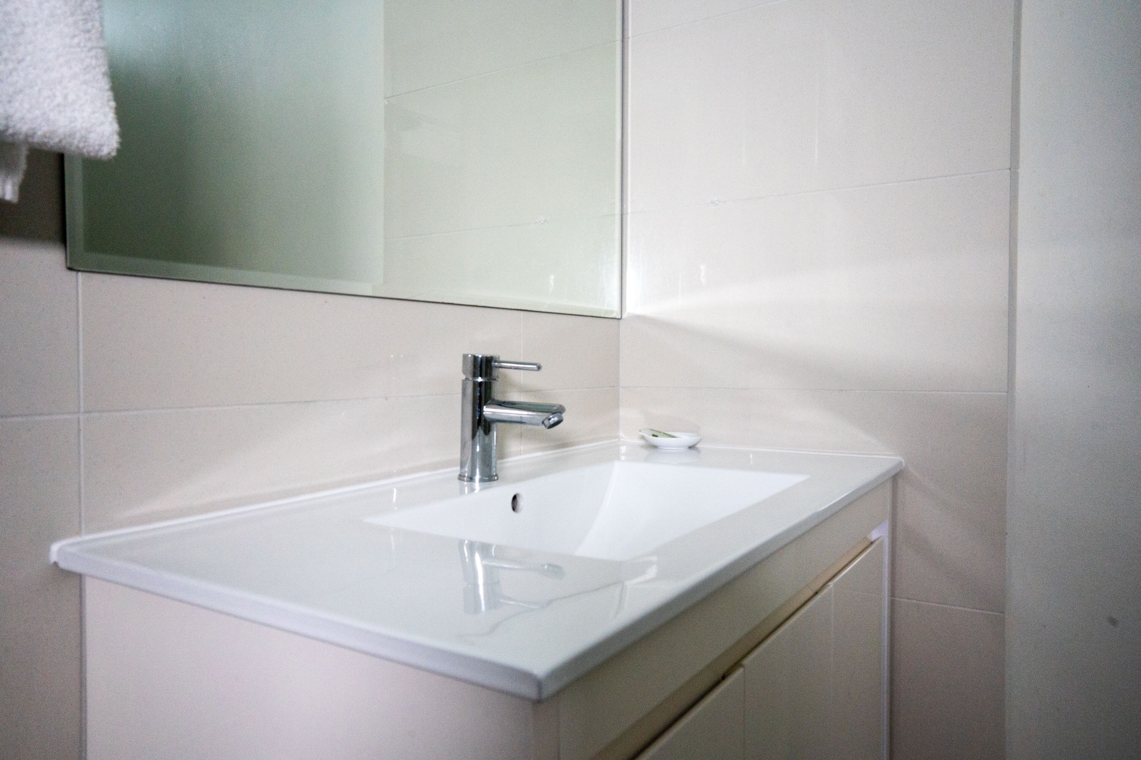 A bathroom with a white sink, chrome faucet, and a mirror above it.