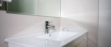 A bathroom with a white sink, chrome faucet, and a mirror above it.