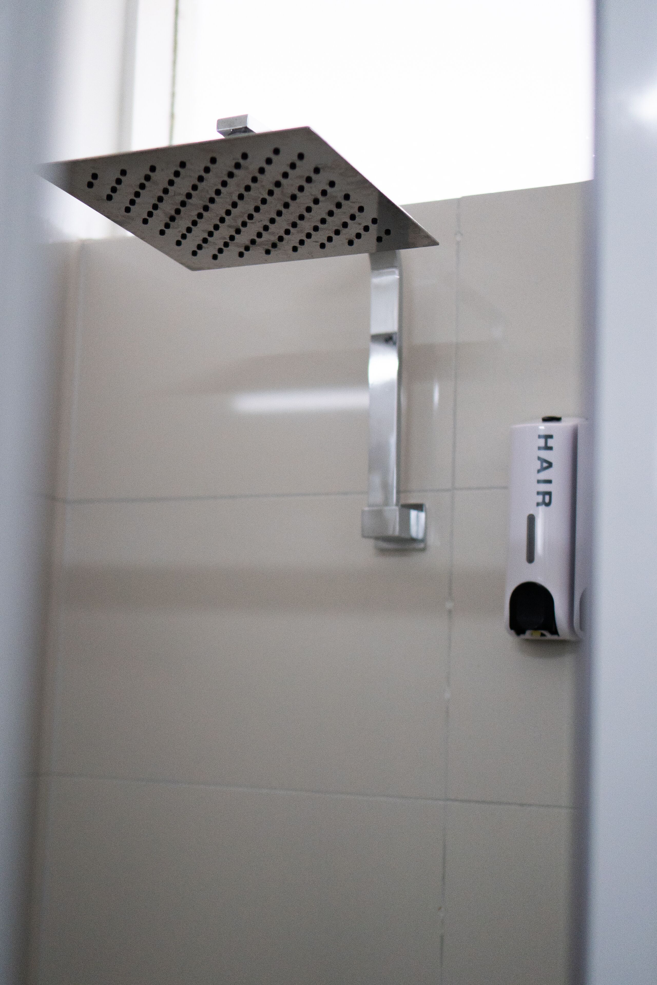Un cabezal de ducha de diseño cuadrado y un secador de manos montado en la pared.