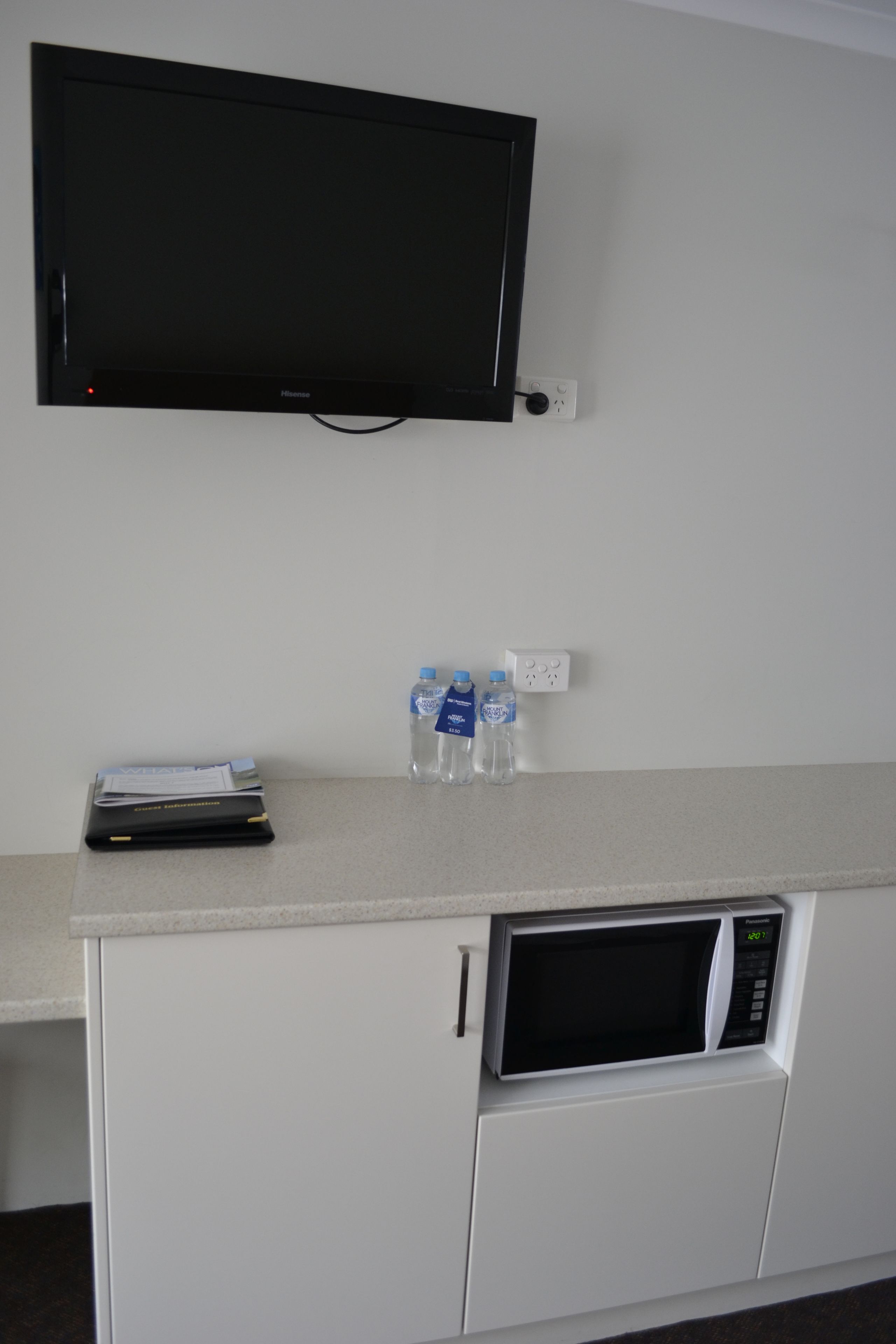 A kitchenette with a flat-screen TV, a microwave, and a water dispenser.