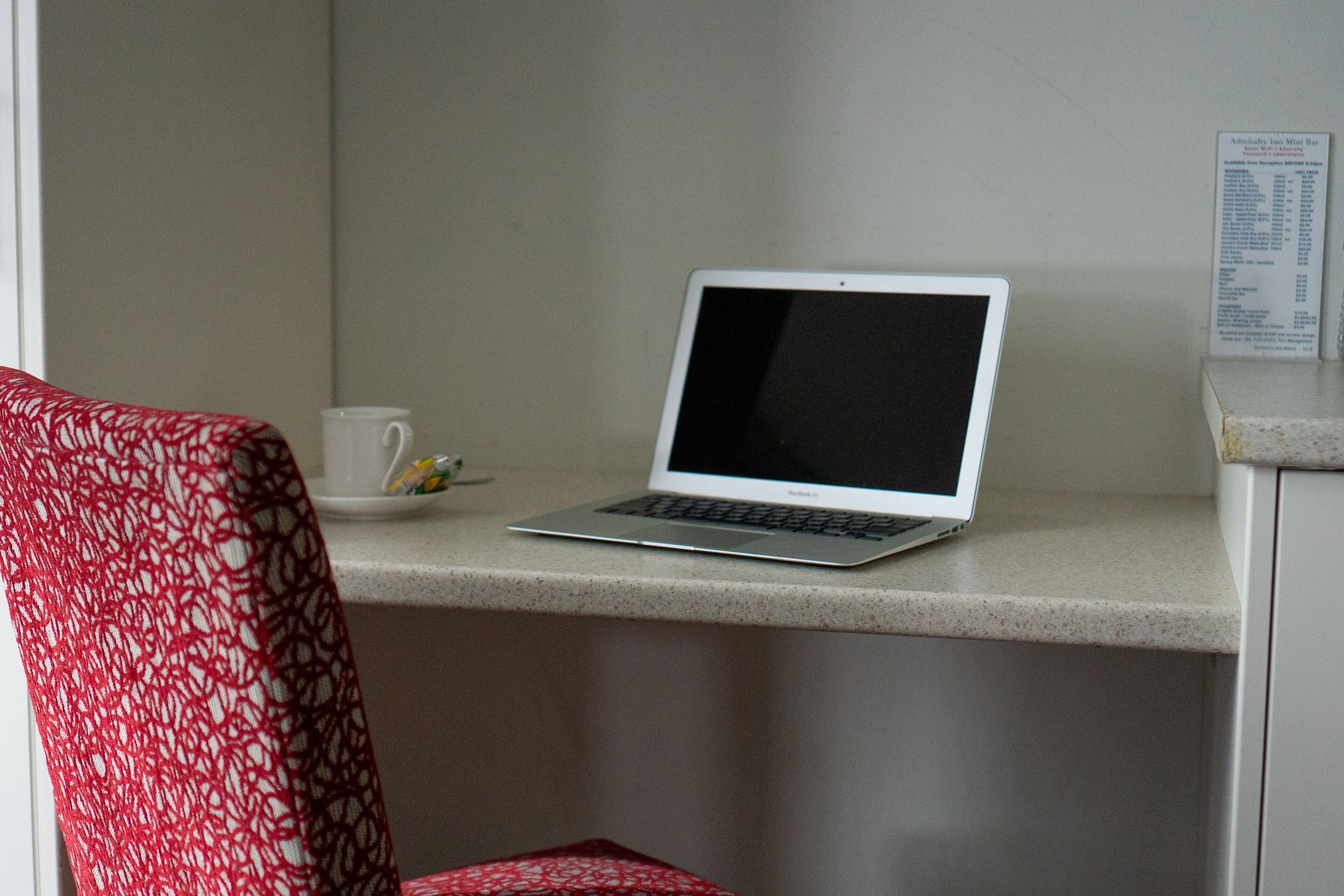 A laptop on a countertop with a menu board in the background.