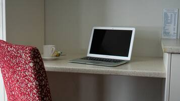 A laptop on a countertop with a menu board in the background.