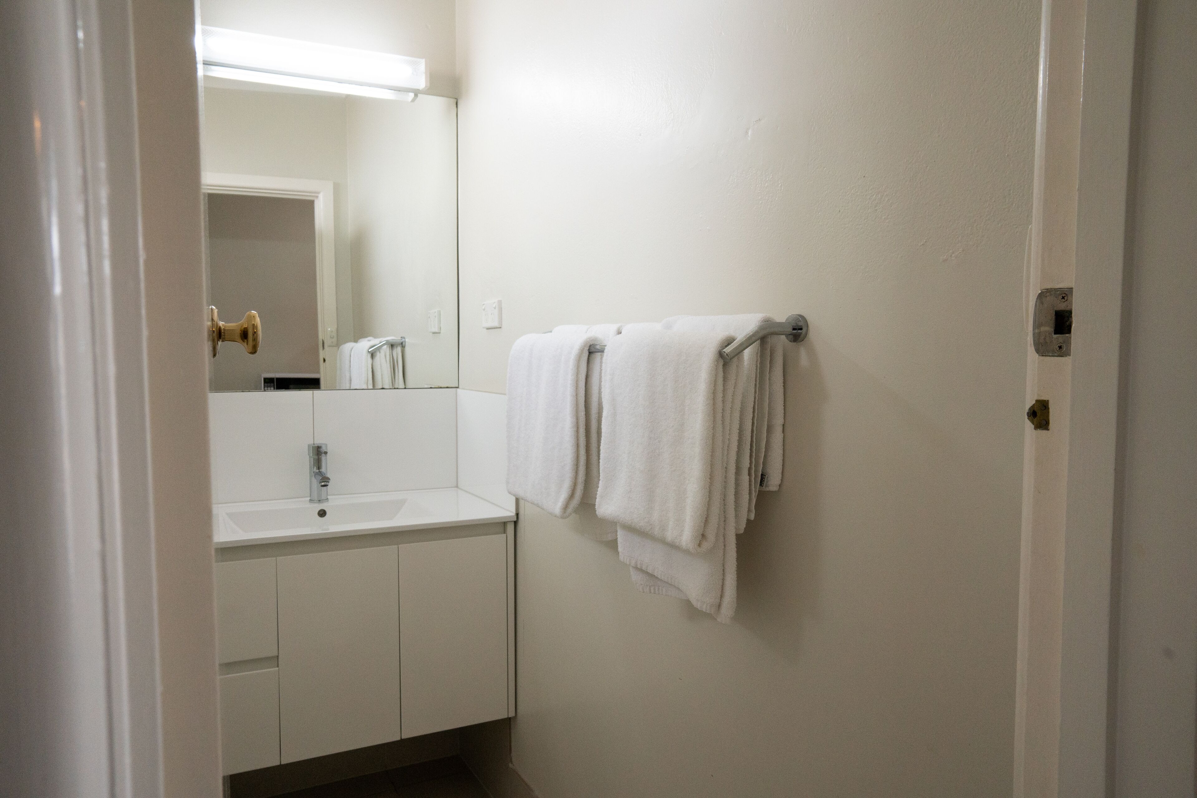 A bathroom with a white sink, a mirror, and two towels hanging on a towel rack.