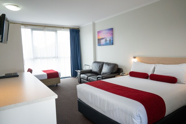 A hotel room with a bed, a desk, a chair, and a sofa. - Admiralty Inn (Geelong)