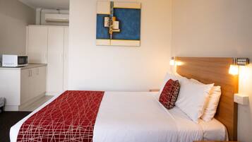 Habitación de hotel con cama, microondas, armario y una obra de arte colgada en la pared.