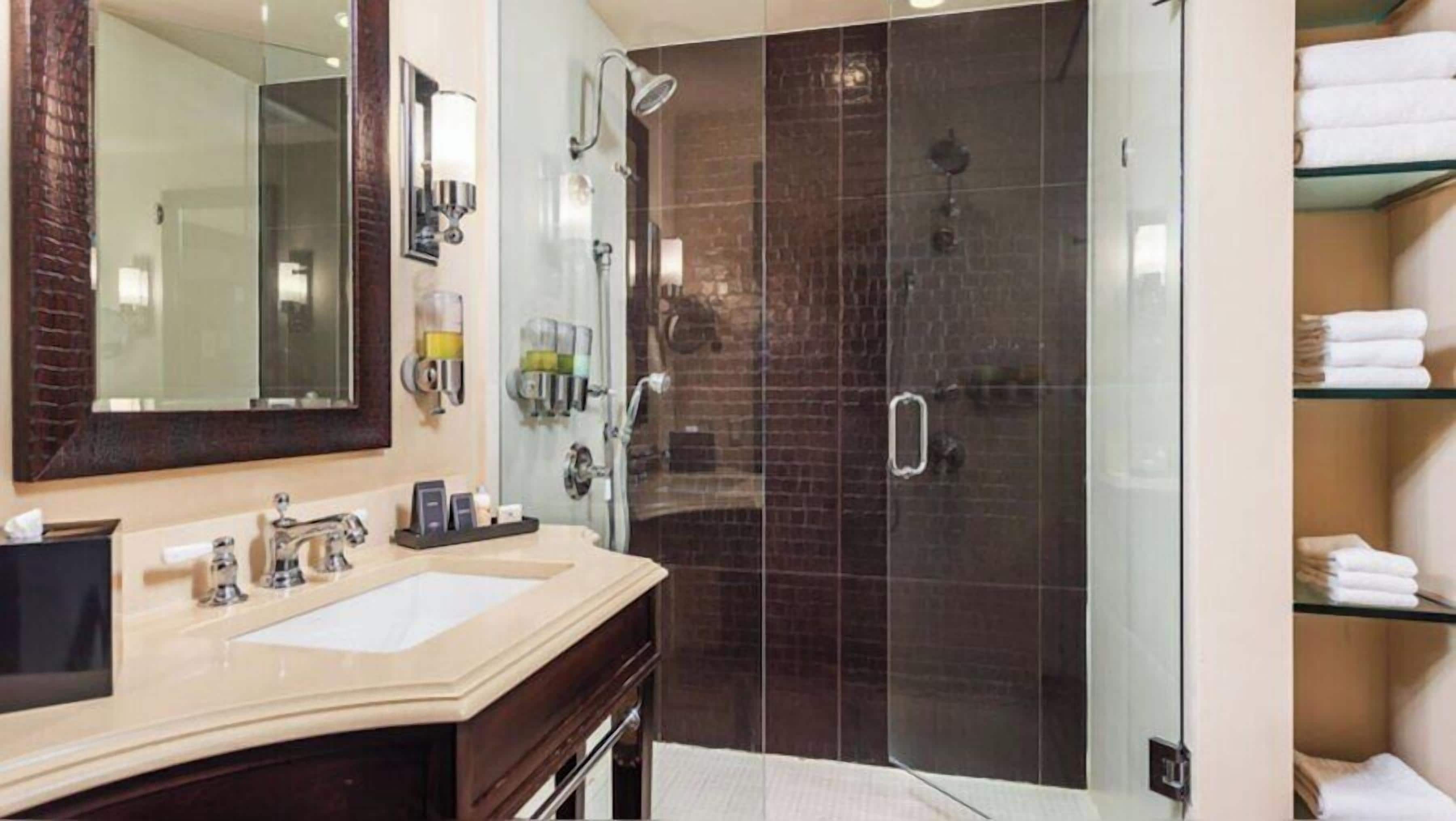 A bathroom with a sink, mirror, and a glass-enclosed shower.