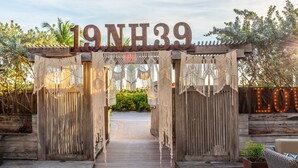 A wooden archway with the number "19NH39" and macrame decorations, leading to a pathway.