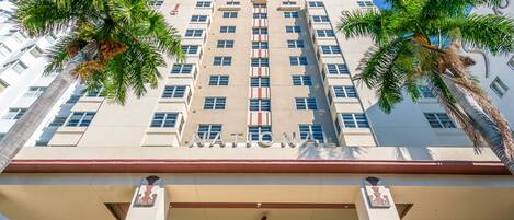A tall, white building with the word "NATIONAL" on the facade, palm trees, and a central entrance with a fan.
