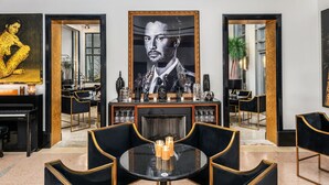 A modern interior with a piano, a dining area, and a large framed portrait. - The National Hotel Miami Beach (Miami Beach)