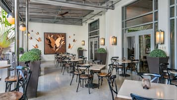 An indoor dining area with tables and chairs, a ceiling fan, and wall-mounted lights.