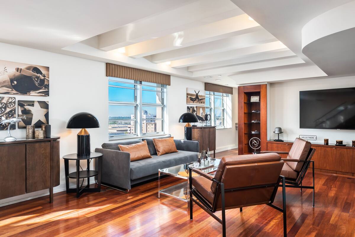A modern living room with a grey sofa, brown leather chairs, a coffee table, and a TV.